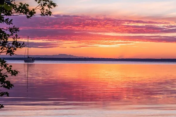 Einfamilienhaus Am Hafen 21 in Zieslow — stimmungsvoller Sonnenuntergang am See mit Segelboot und farbigem Himmel  Am Hafen 21