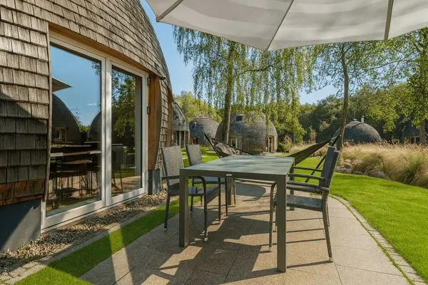 Terrassenblick mit stilvollem Esstisch, Hängematte und Sonnenschirm – eingerahmt von einzigartigen Rundhäusern  Nordkugel