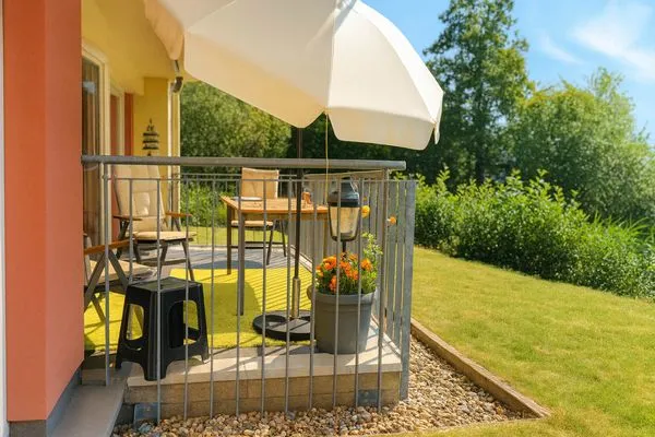 Balkon mit Tisch, Stühlen und Sonnenschirm.  Granata