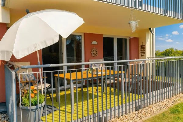 Balkon mit Tisch, Stühlen und Sonnenschirm.  Granata