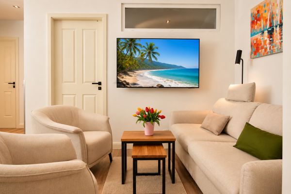 Wohnzimmer mit Sofa, Sesseln und TV