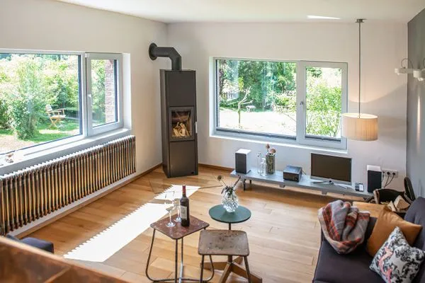 Helles Wohnzimmer mit Kaminofen und Blick in den Garten  Ferienhaus Friedrich 15