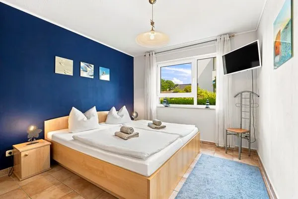 Schlafzimmer mit Doppelbett, Kleiderschrank und TV Residenz am Strand Wohnung 4-58