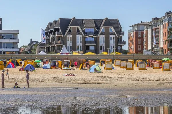 Strand mit zahlreichen Sonnenschirmen und Strandkörben, umgeben von Wattlandschaft in Cuxhaven-Duhnen vor der Residenz Meeresbrandung.  Residenz Meeresbrandung Nr. 35