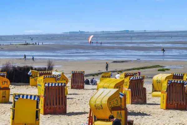 Strandkörbe am sonnigen Sandstrand von Cuxhaven-Duhnen, im Hintergrund das Wattenmeer und die Insel Neuwerk.  Haus Pacific Duhnen Nr. 91
