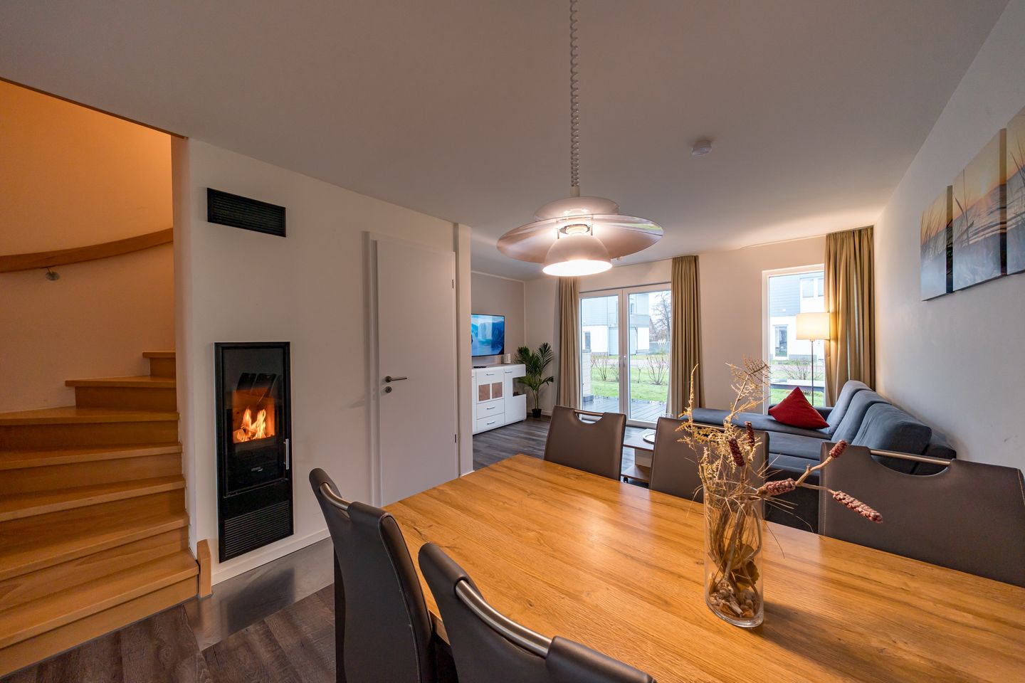 NordseeResort Friesland Ferienhäuser NordseeResort Friesland 11 Schillig - Wohn-Essbereich mit Couch, Esstisch und Kamin