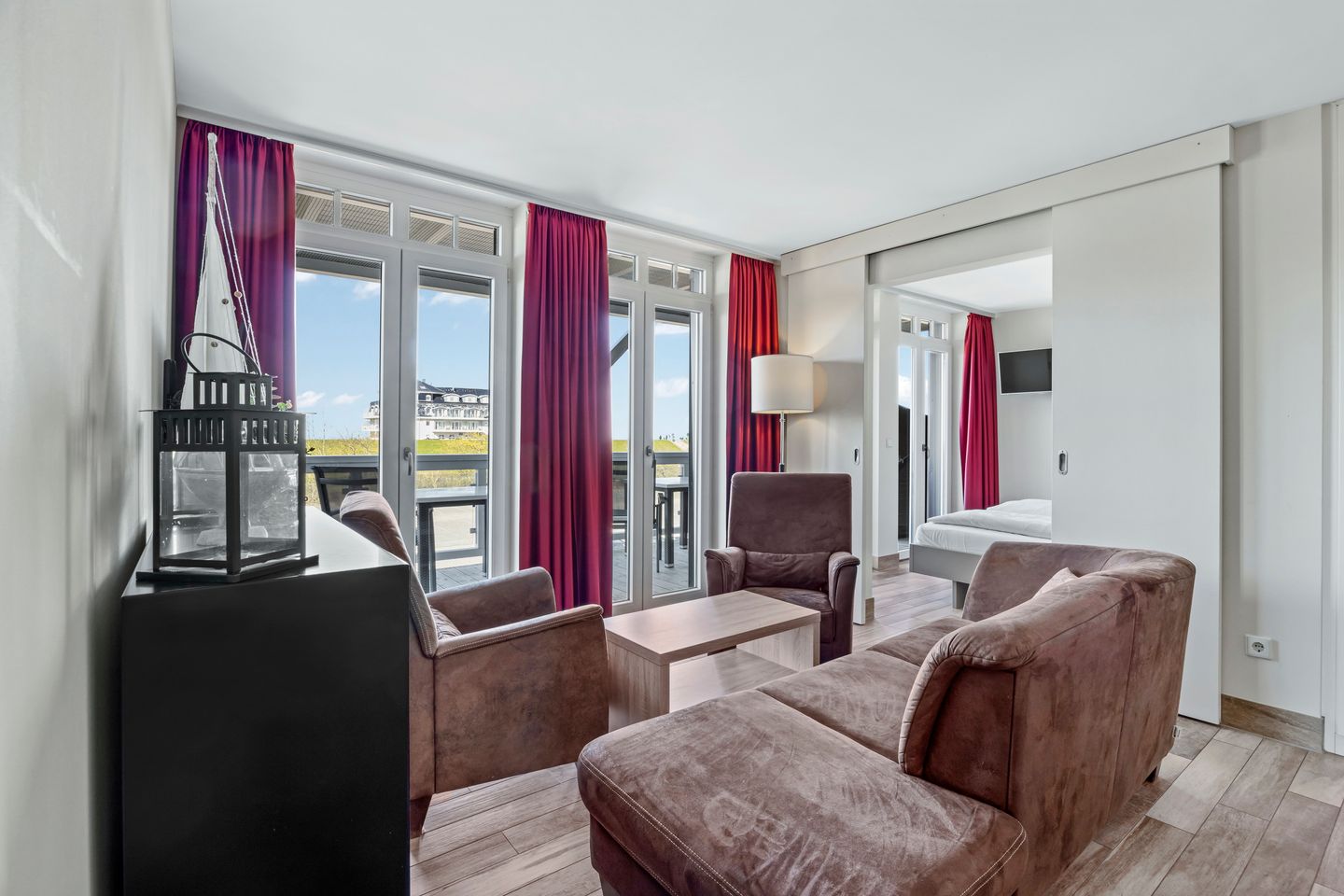 Resort Deichgraf Resort Deichgraf 27-14 Wremen - Wohnbereich mit Sofa, Sessel, Couchtisch mit Zugang zum Balkon