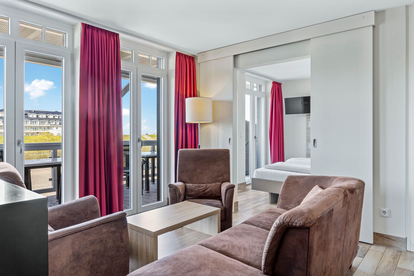 Resort Deichgraf Resort Deichgraf 27-14 Wremen - Wohnbereich mit Sofa, Sessel, Couchtisch mit Zugang zum Balkon