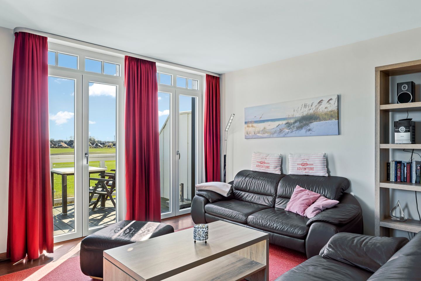 Resort Deichgraf Resort Deichgraf 27-21 Wremen - Wohnbereich mit Sofa, Sessel, Couchtisch und Zugang zum Balkon