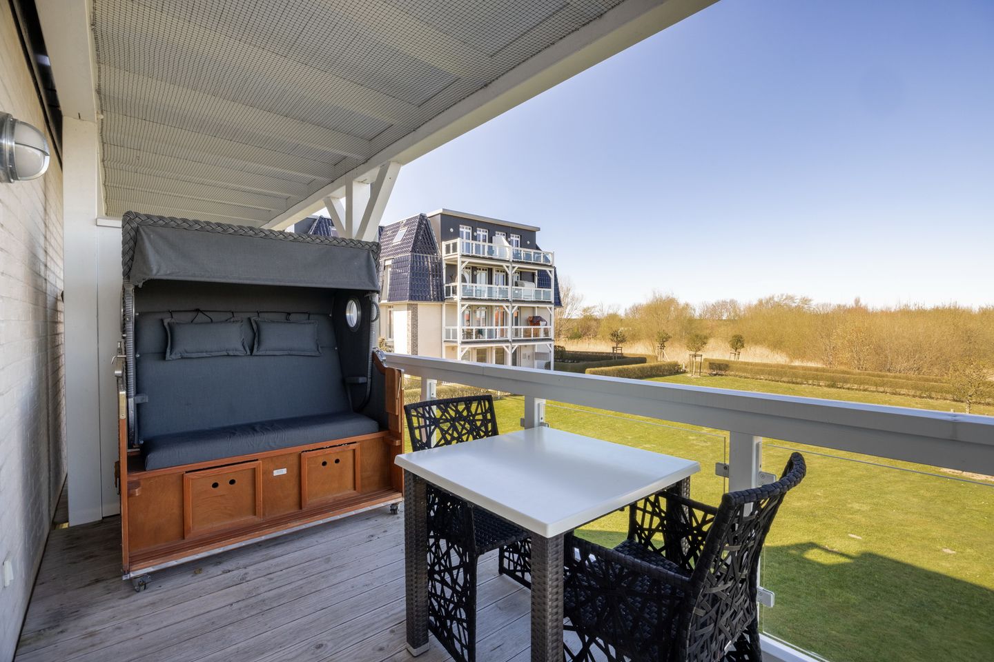 Resort Deichgraf Resort Deichgraf 31-07 Wremen - Überdachter Balkon mit Sitzgelegenheit und Strandkorb