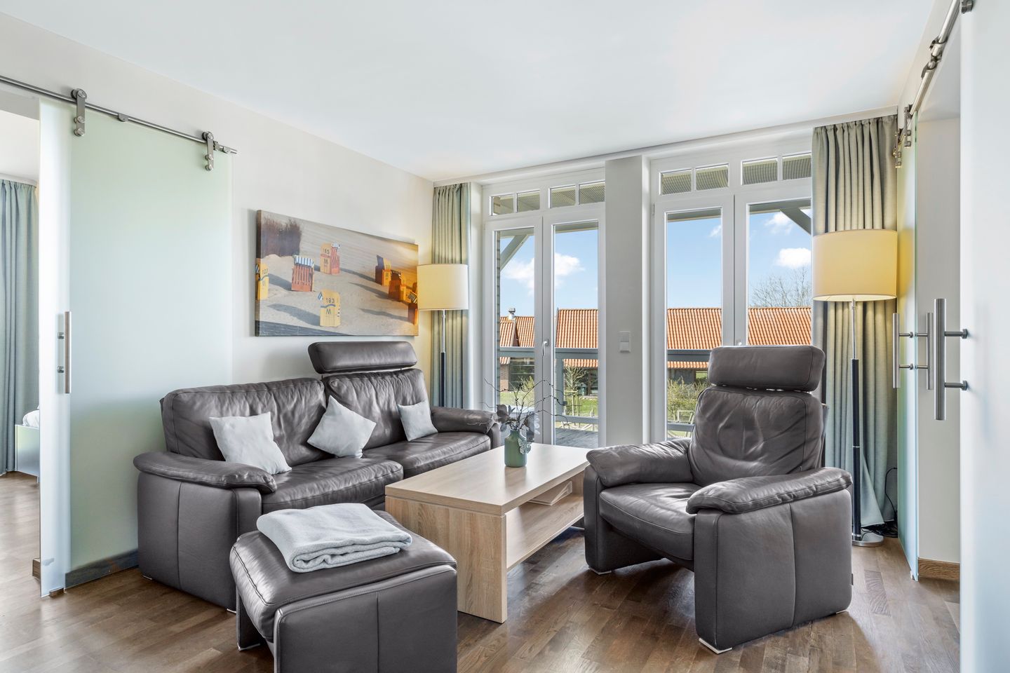 Resort Deichgraf Resort Deichgraf 31-11 Wremen - Wohnbereich mit Sofa, Sessel, Couchtisch und Zugang zum Balkon