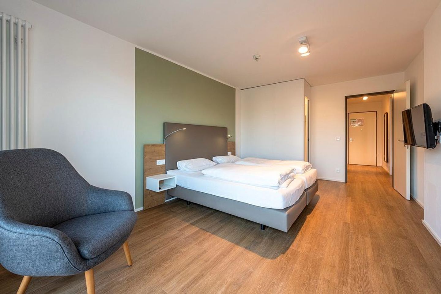 Apartmentvilla Anna See Apartmentvilla Anna See 2-13 Langeoog - Schlafzimmer mit Boxspringbett, Sessel und TV