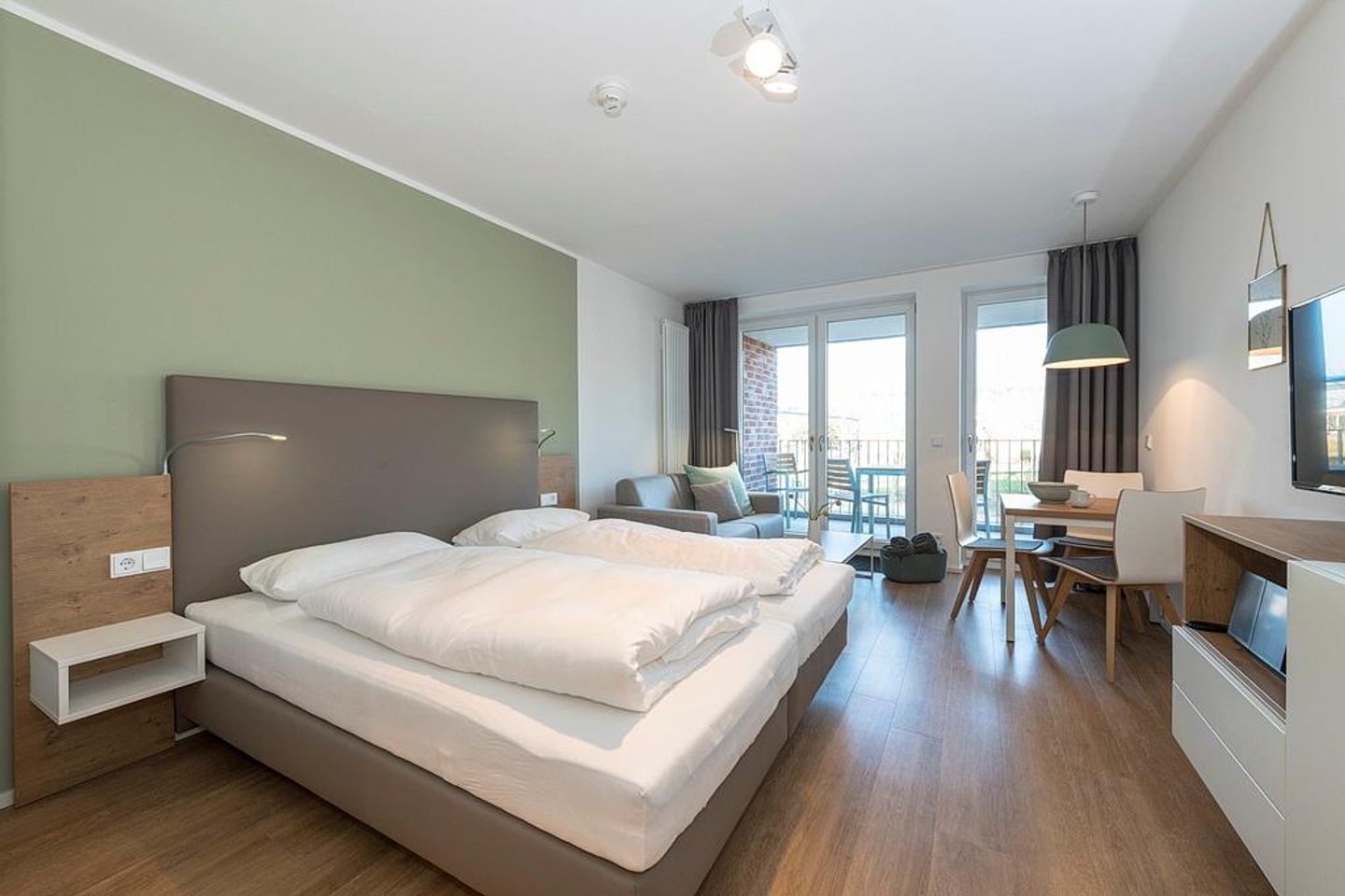 Apartmentvilla Anna See Apartmentvilla Anna See 2-14 Langeoog - Wohnbereich mit Boxspringbett und Zugang zum überdachten Balkon