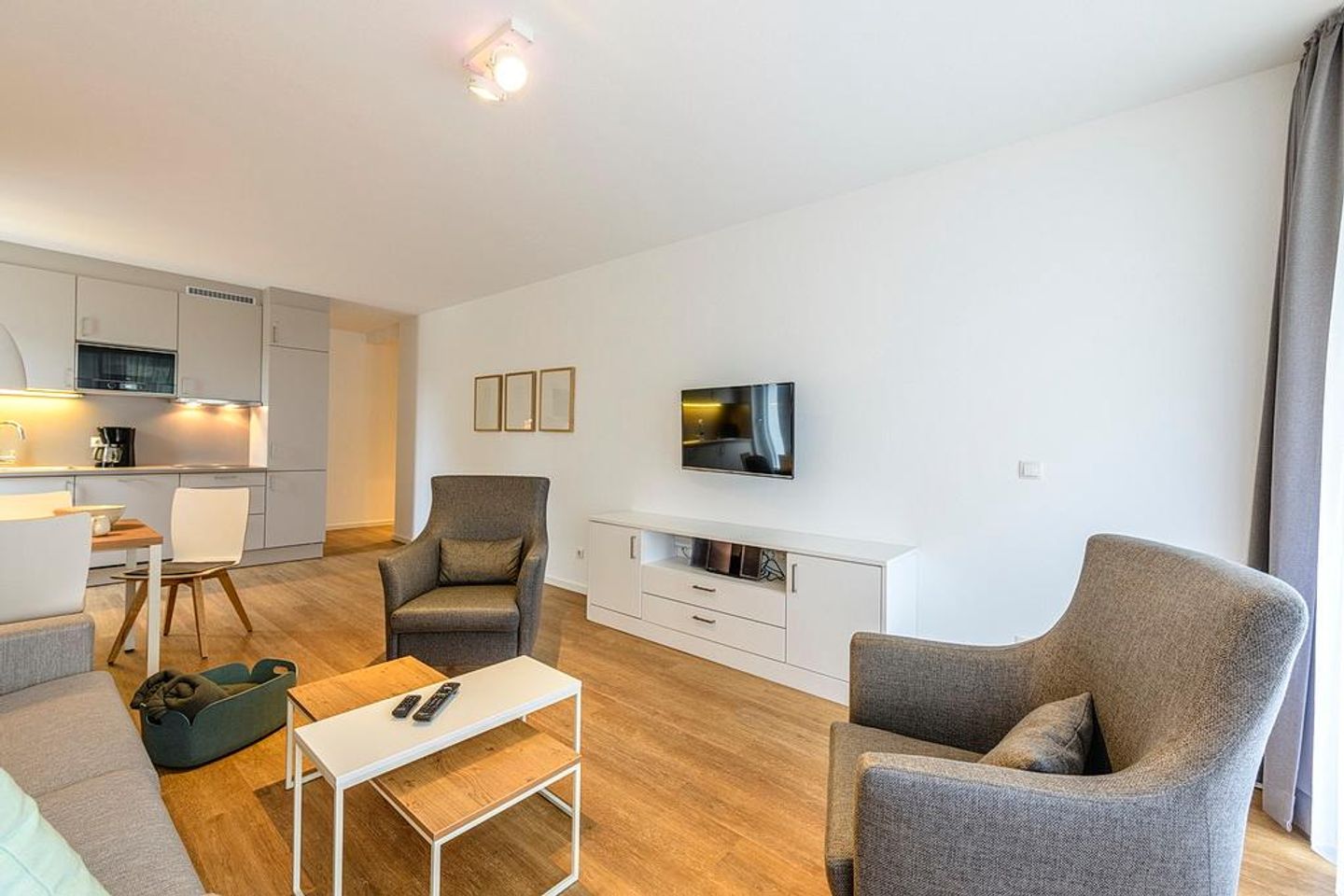 Deichhäuser Anna Küste Deichhäuser Anna Küste 1-10 Bensersiel - Wohn/Essbereich mit Sesseln, Couch, TV und Küchenzeile