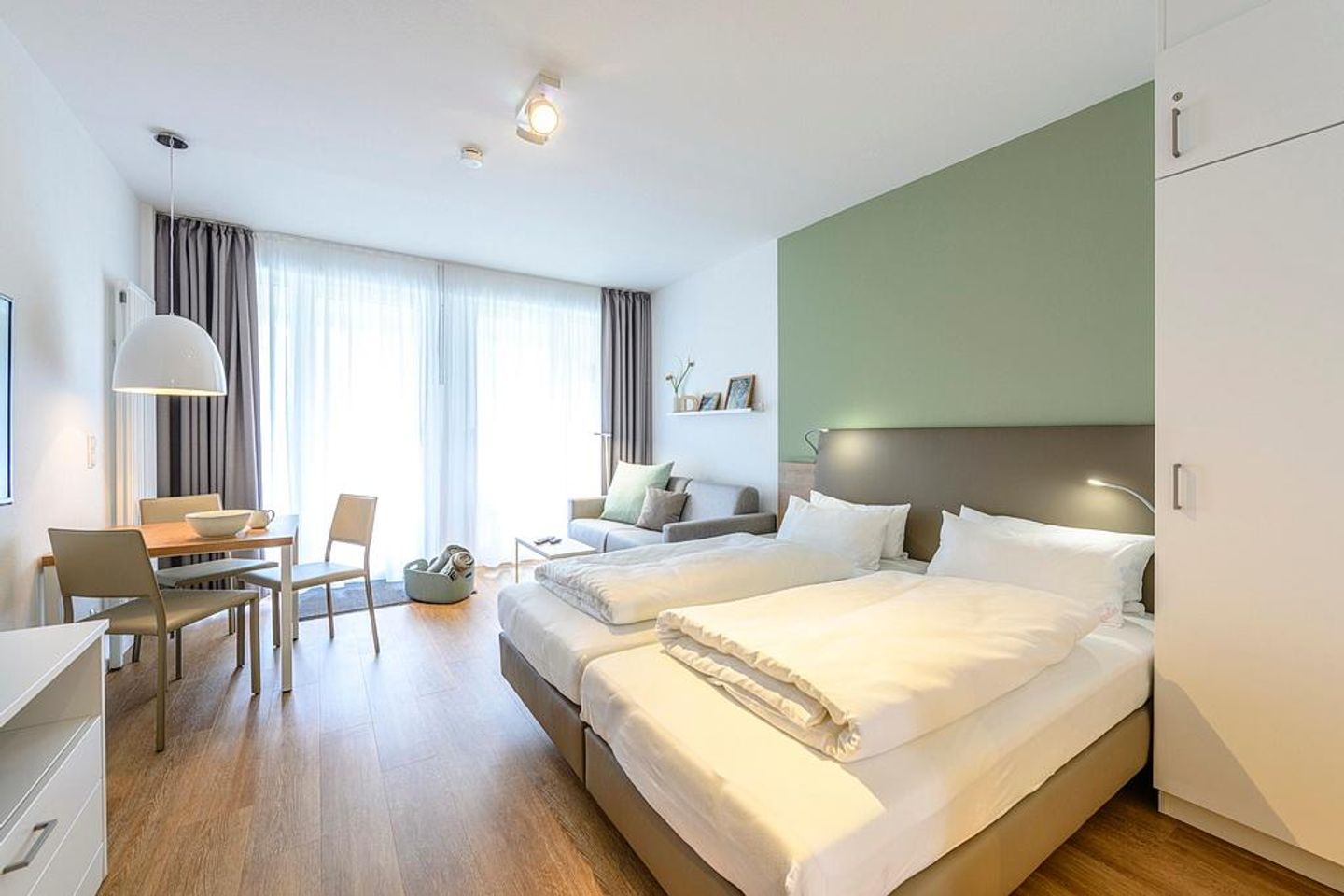 Deichhäuser Anna Küste Deichhäuser Anna Küste 1-12 Bensersiel - Wohn/Essbereich mit Doppelbett, Esstisch und Couch