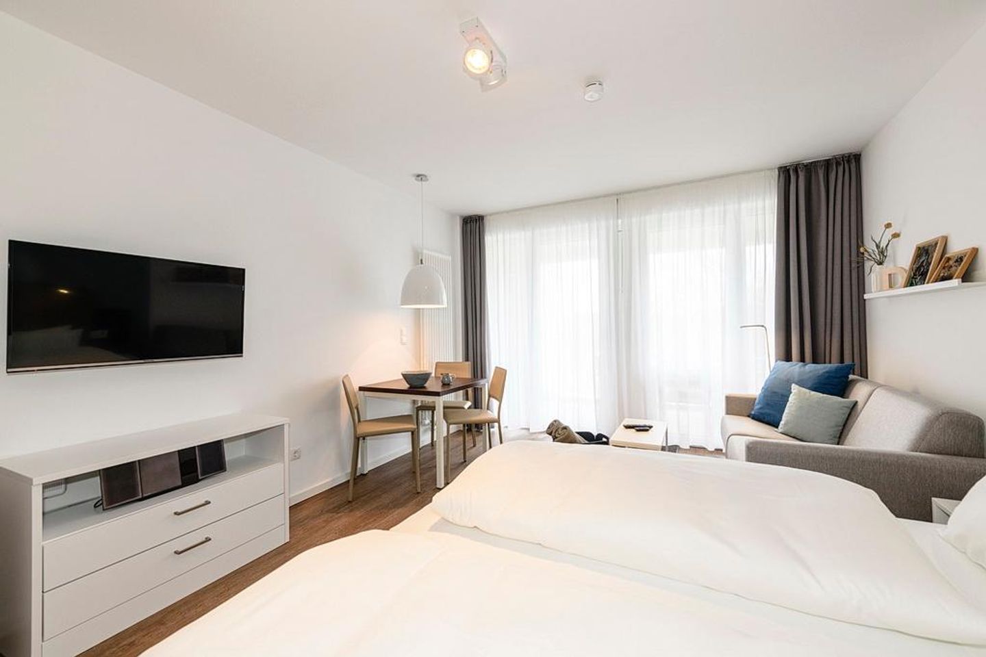 Deichhäuser Anna Küste Deichhäuser Anna Küste 1-22 Bensersiel - Wohn/Essbereich mit Doppelbett, Couch, Esstisch und TV