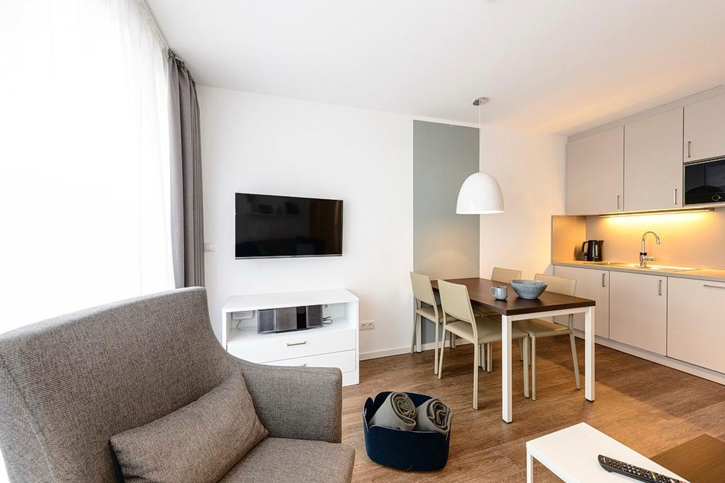 Deichhäuser Anna Küste Deichhäuser Anna Küste 1-31 Bensersiel - Wohn/Essbereich mit Sessel, Esstisch, Küchenzeile und TV