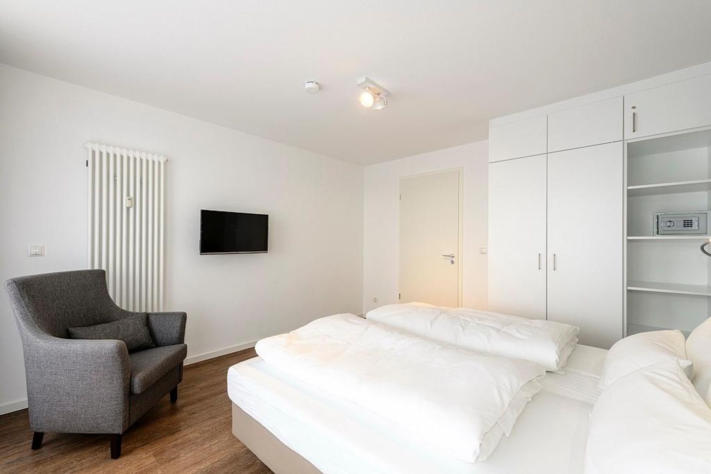 Deichhäuser Anna Küste Deichhäuser Anna Küste 1-31 Bensersiel - Schlafzimmer mit Doppelbett, Sessel, Kleiderschrank und TV