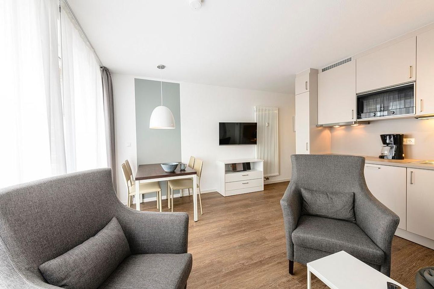 Deichhäuser Anna Küste Deichhäuser Anna Küste 1-33 Bensersiel - Wohn/Essbereich mit Sesseln, Esstisch, Küchenzeile und TV