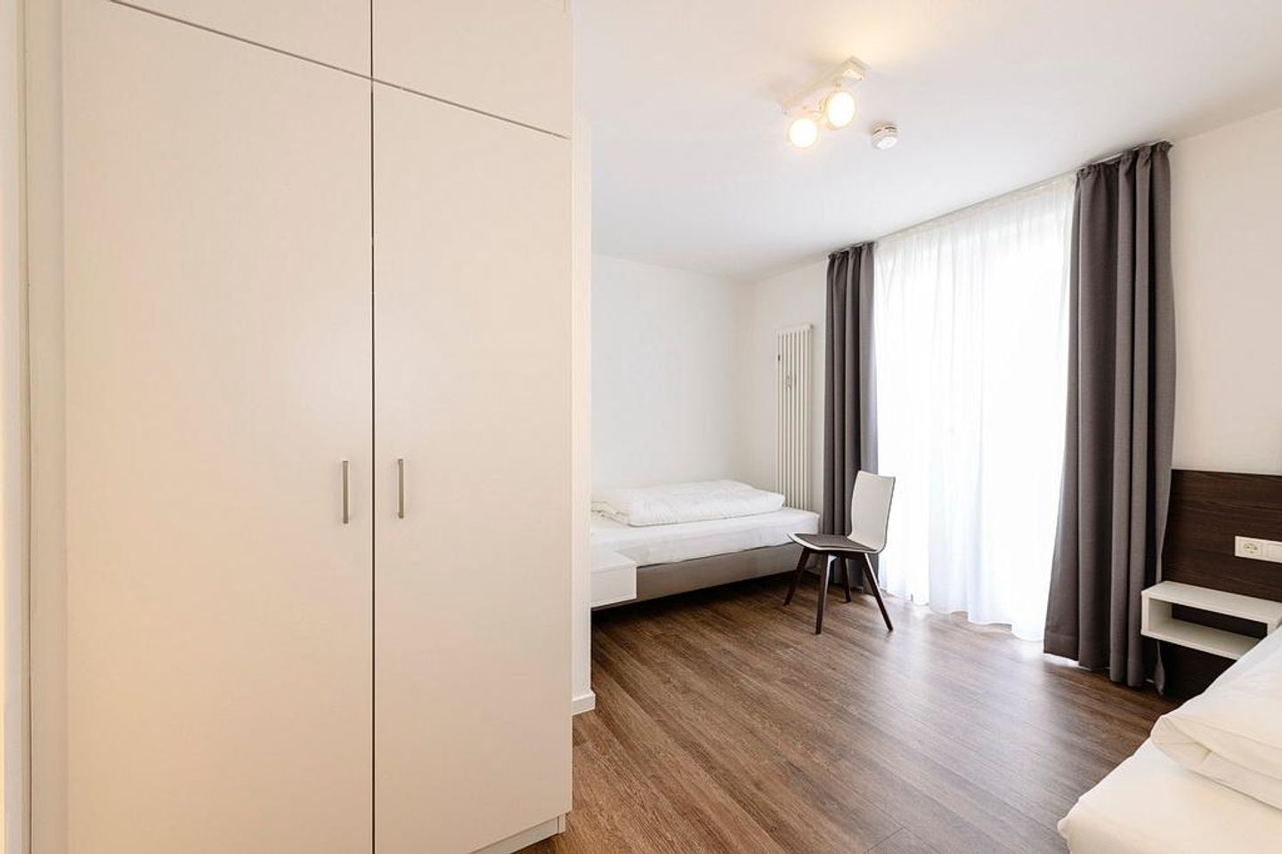 Deichhäuser Anna Küste Deichhäuser Anna Küste 1-34 Bensersiel - Schlafzimmer mit zwei Einzelbetten, Stuhl und Kleiderschrank