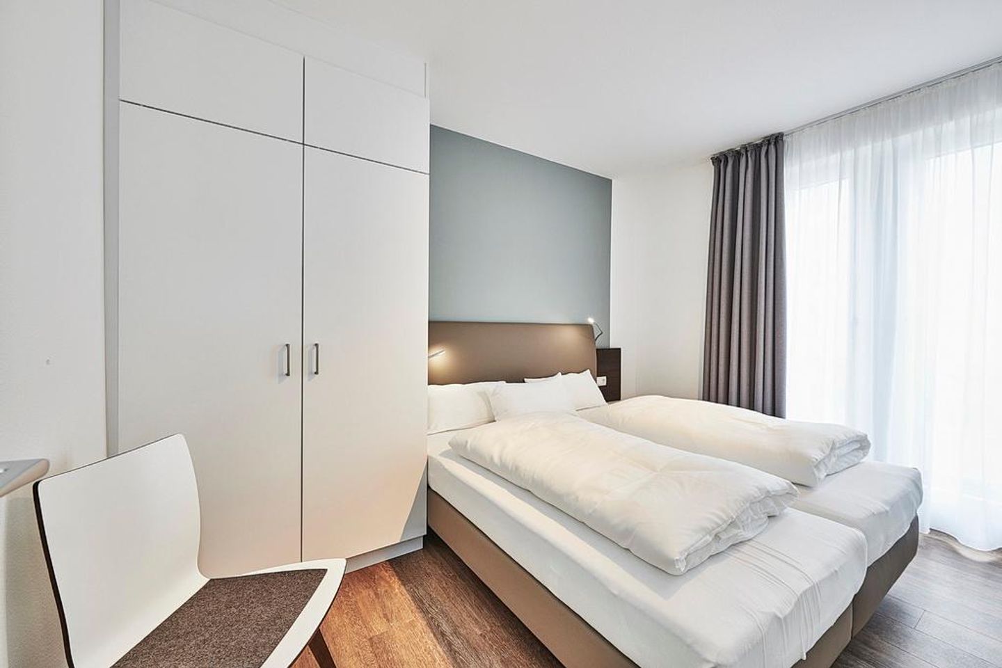 Deichhäuser Anna Küste Deichhäuser Anna Küste 2-13 Bensersiel - Schlafzimmer mit Doppelbett, Stuhl und Kleiderschrank