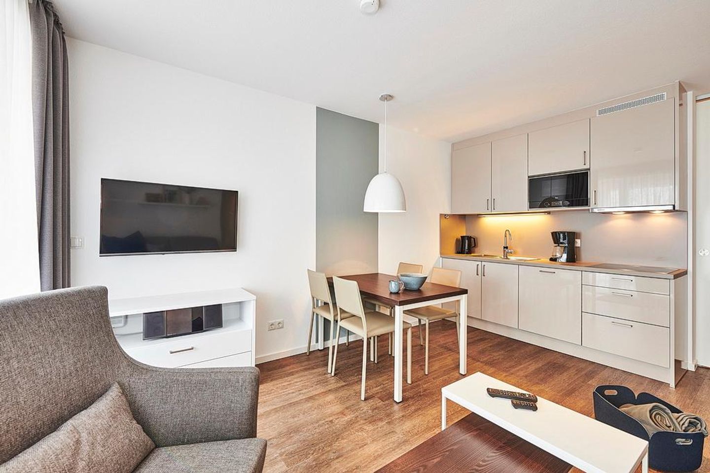 Deichhäuser Anna Küste Deichhäuser Anna Küste 2-21 Bensersiel - Wohn/Essbereich mit Sessel, Esstisch, Küchenzeile und TV