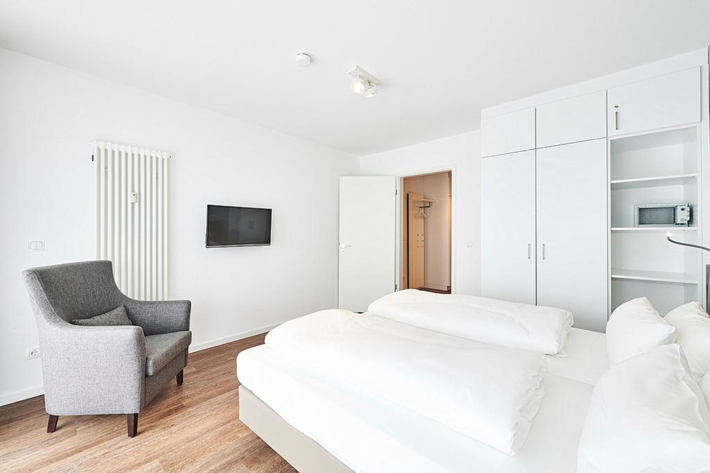 Deichhäuser Anna Küste Deichhäuser Anna Küste 2-21 Bensersiel - Schlafzimmer mit Doppelbett, Sessel, TV und Kleiderschrank