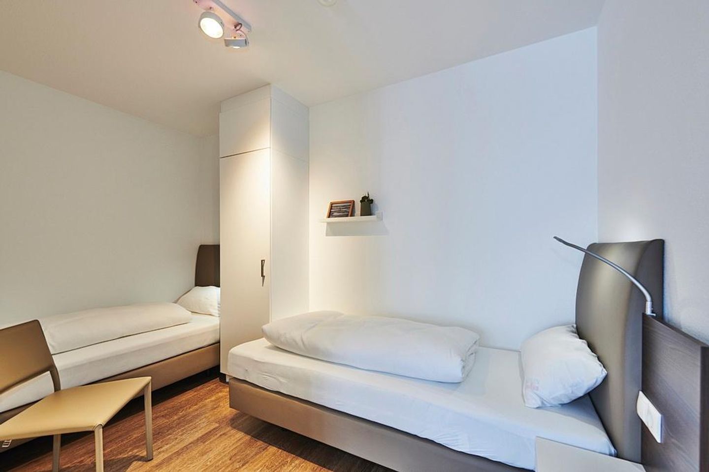 Deichhäuser Anna Küste Deichhäuser Anna Küste 2-21 Bensersiel - Schlafzimmer mit zwei Einzelbetten, Stuhl und Kleiderschrank