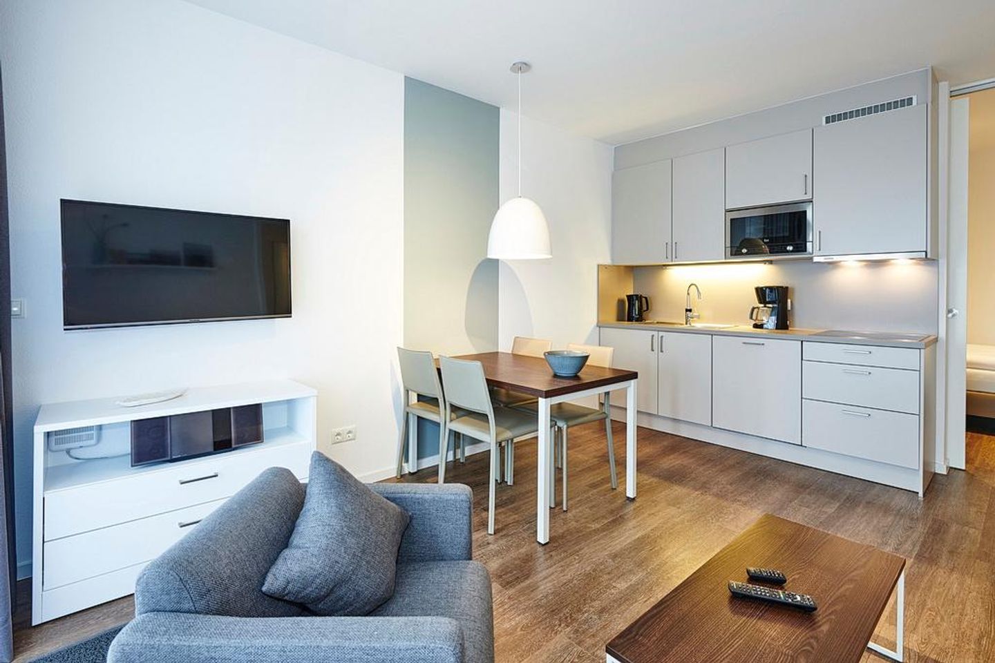 Deichhäuser Anna Küste Deichhäuser Anna Küste 3-11 Bensersiel - Wohn/Essbereich mit Sessel, Esstisch, TV und Küchenzeile