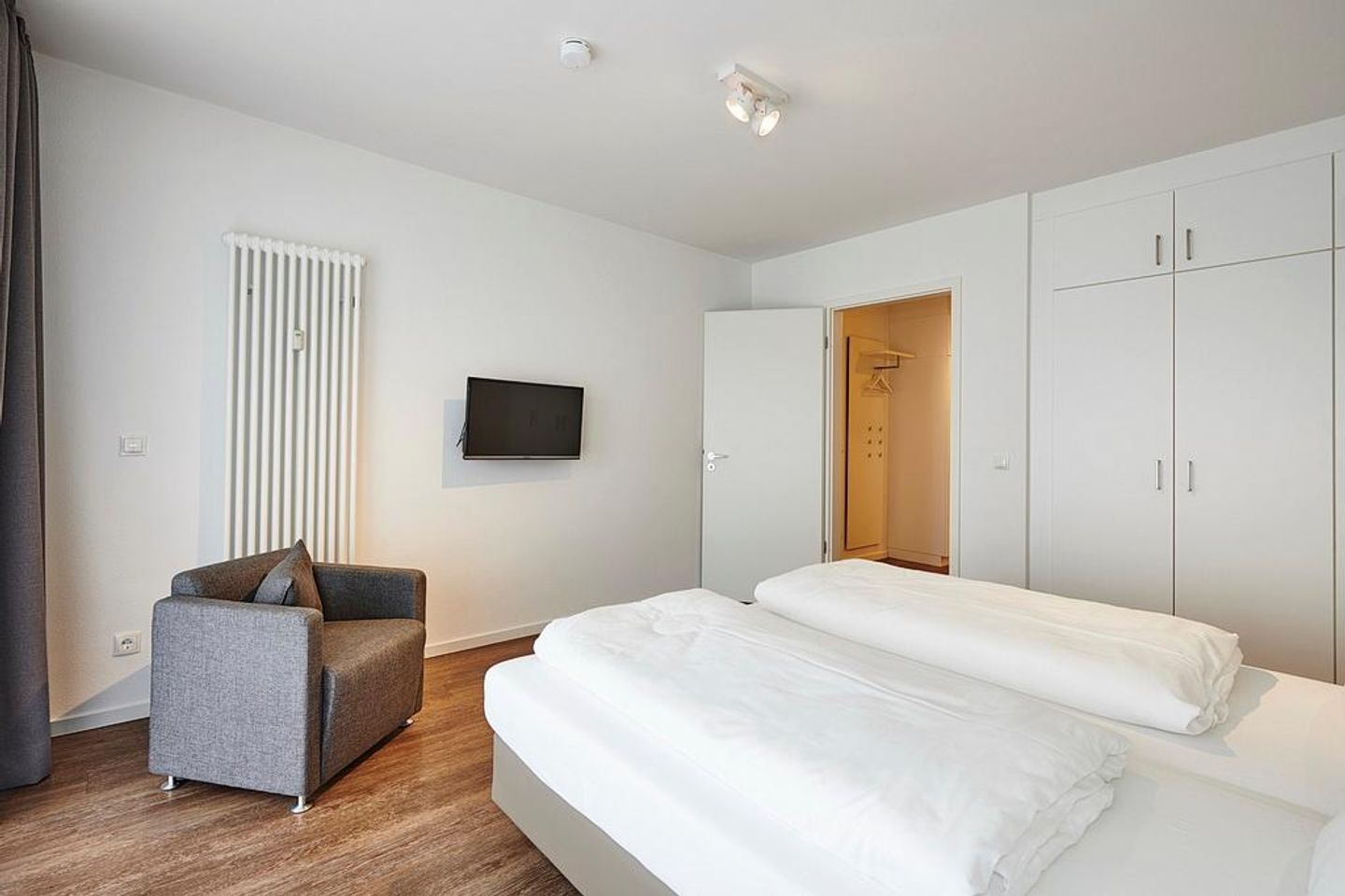 Deichhäuser Anna Küste Deichhäuser Anna Küste 3-11 Bensersiel - Schlafzimmer mit Doppelbett, Sessel, Kleiderschrank und TV