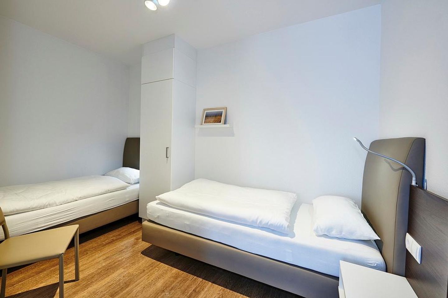 Deichhäuser Anna Küste Deichhäuser Anna Küste 3-11 Bensersiel - Schlafzimmer mit zwei Einzelbetten, Stuhl und Kleiderschrank