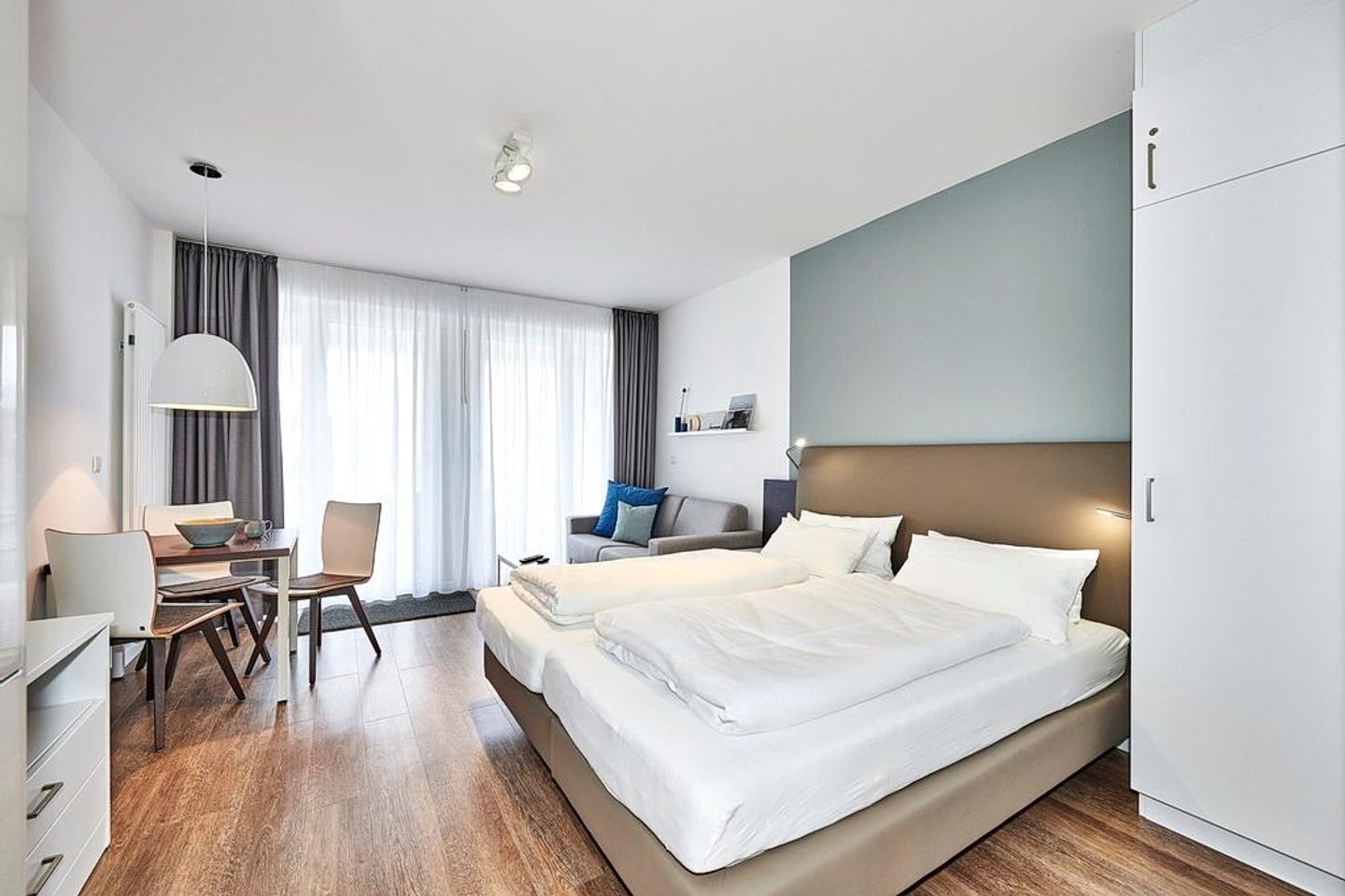 Deichhäuser Anna Küste Deichhäuser Anna Küste 4-12 Bensersiel - Wohn-, Ess-, Schlafbereich mit Couch, Esstisch und Sitzgelegenheit und Doppelbett