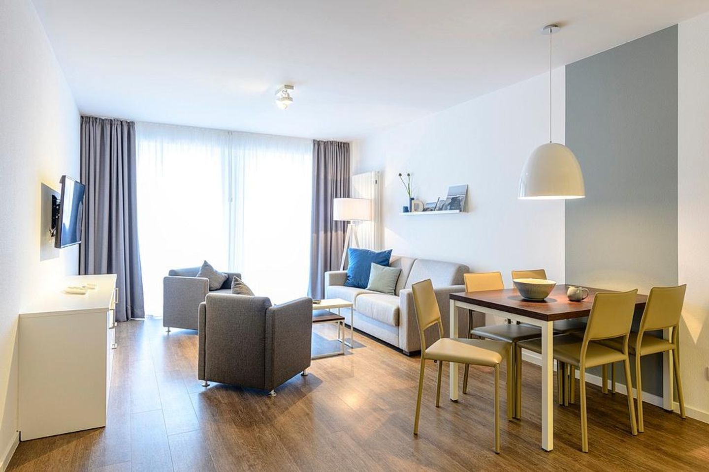 Deichhäuser Anna Küste Deichhäuser Anna Küste 4-20 Bensersiel - Wohn-Essbereich mit Couch, Sessel, Esstisch und Zugang zum Balkon