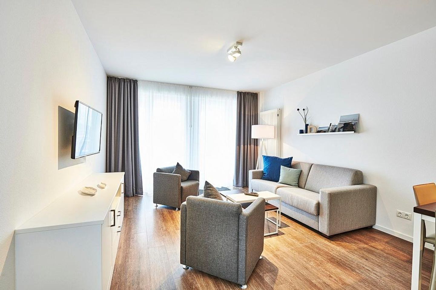 Deichhäuser Anna Küste Deichhäuser Anna Küste 4-20 Bensersiel - Wohnbereich mit Sofa, Sessel, Couchtisch und Zugang zum Balkon