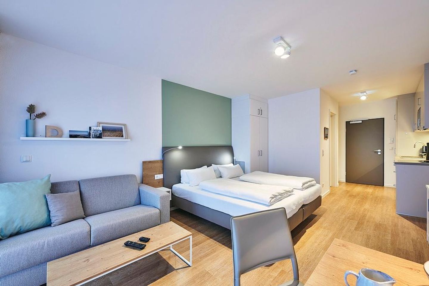 Deichhäuser Anna Küste Deichhäuser Anna Küste 4-22 Bensersiel - Wohn-Ess-Schlafbereich mit Sofa, Esstisch, Sitzgelegenheit und Doppelbett sowie Zugang zum Balkon