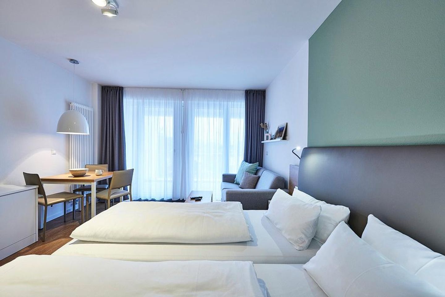 Deichhäuser Anna Küste Deichhäuser Anna Küste 4-22 Bensersiel - Wohn-Ess-Schlafbereich mit Sofa, Esstisch, Sitzgelegenheit und Doppelbett sowie Zugang zum Balkon