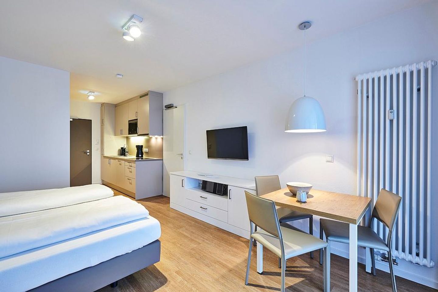 Deichhäuser Anna Küste Deichhäuser Anna Küste 4-22 Bensersiel - Wohn-Ess-Schlafbereich mit Sofa, Esstisch, Sitzgelegenheit und Doppelbett sowie Zugang zum Balkon