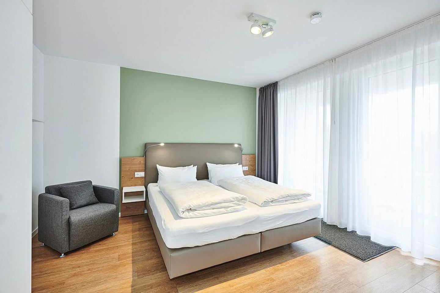 Deichhäuser Anna Küste Deichhäuser Anna Küste 4-24 Bensersiel - Schlafzimmer mit Doppelbett, Sessel und Zugang zum Balkon