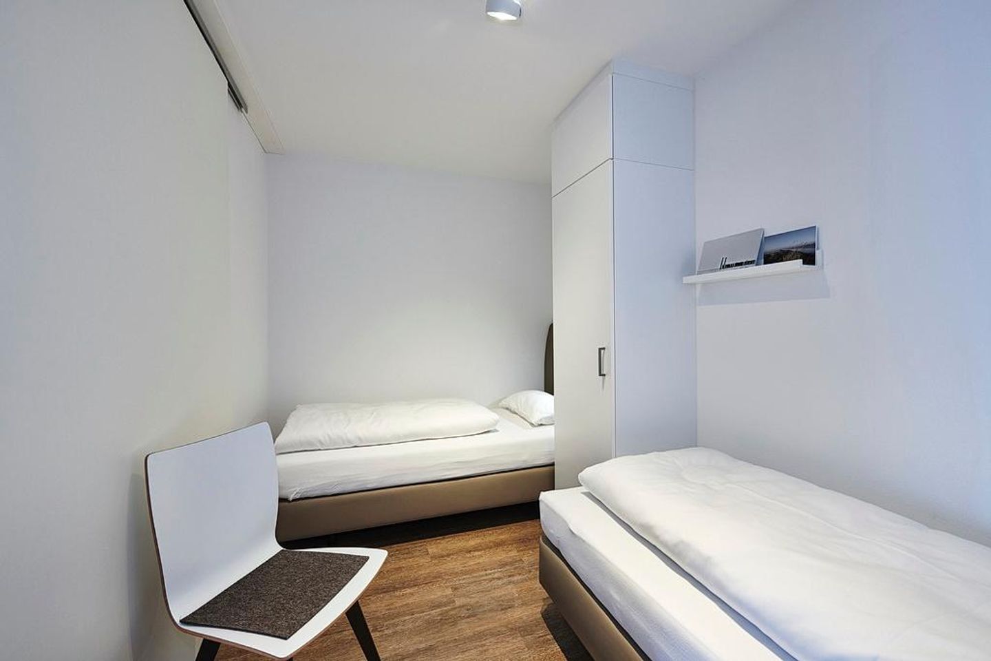 Deichhäuser Anna Küste Deichhäuser Anna Küste 4-31 Bensersiel - Schlafzimmer mit zwei Einzelbetten, Kleiderschrank und Stuhl