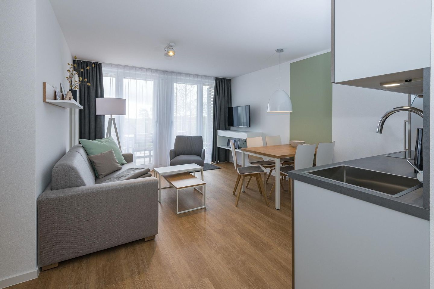 Deichhäuser Anna Küste Deichhäuser Anna Küste 6-31 Bensersiel - Wohn-Essbereich mit Couch, Esstisch, Sitzgelegenheit und Zugang zum Balkon