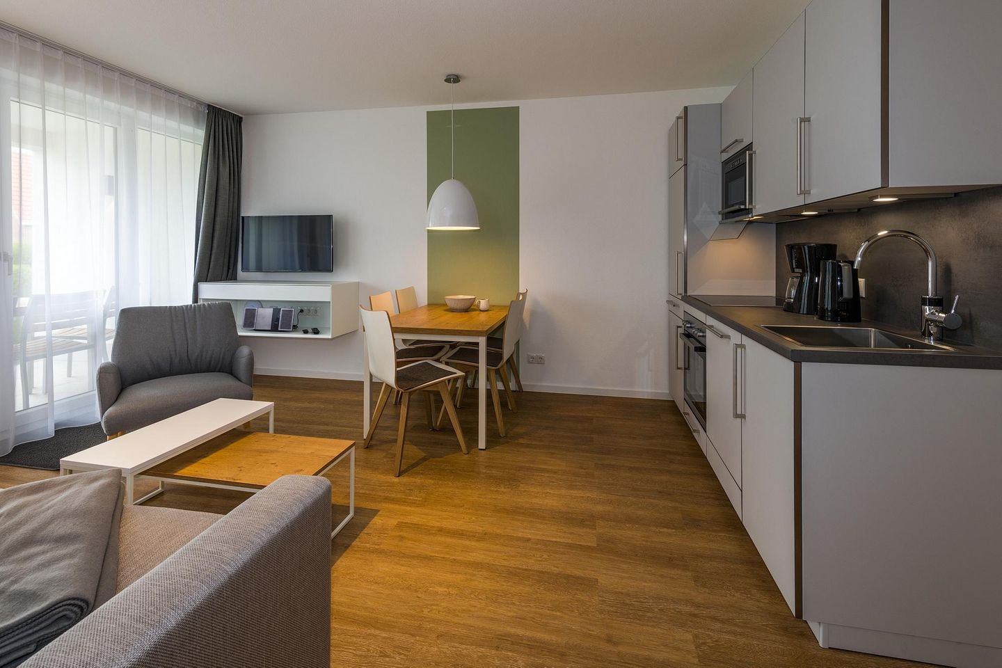 Deichhäuser Anna Küste Deichhäuser Anna Küste 7-11 Bensersiel - Wohn-Essbereich mit Couch, Esstisch, Sitzgelegenheit und Küchenzeile