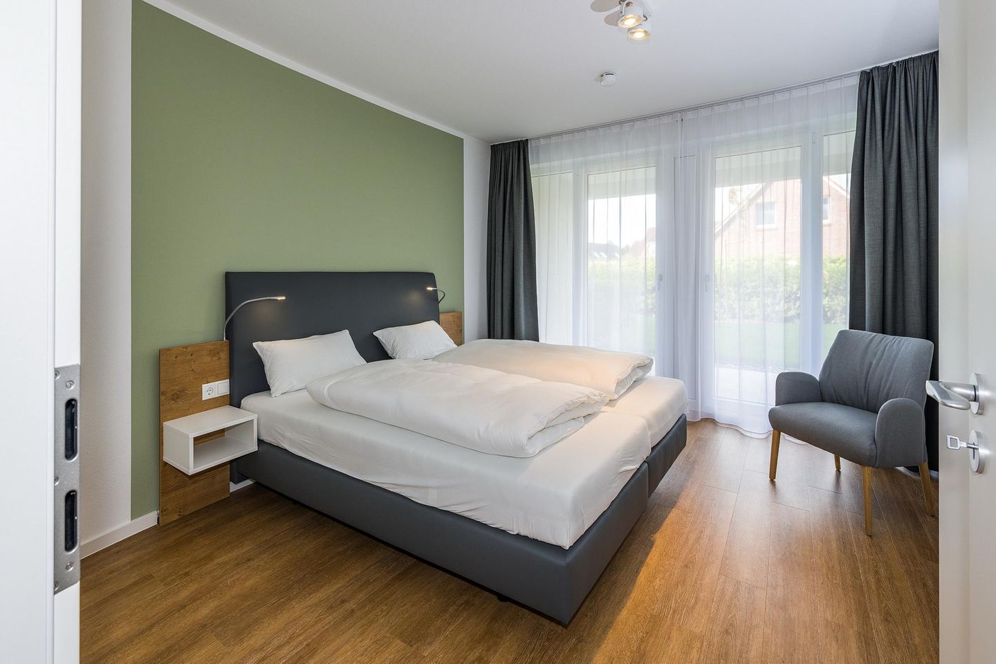 Deichhäuser Anna Küste Deichhäuser Anna Küste 7-11 Bensersiel - Schlafzimmer mit Doppelbett, Sitzgelegenheit und Zugang zur Terrasse