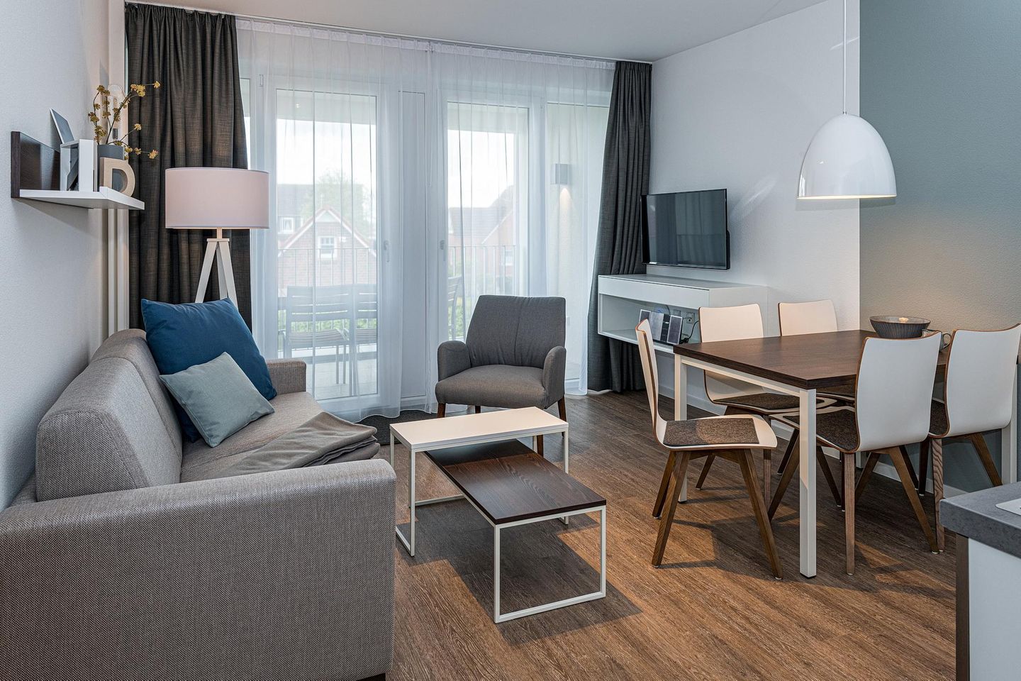 Deichhäuser Anna Küste Deichhäuser Anna Küste 7-21 Bensersiel - Wohn-Essbereich mit Couch, Esstisch, Sitzgelegenheit und Zugang zum Balkon