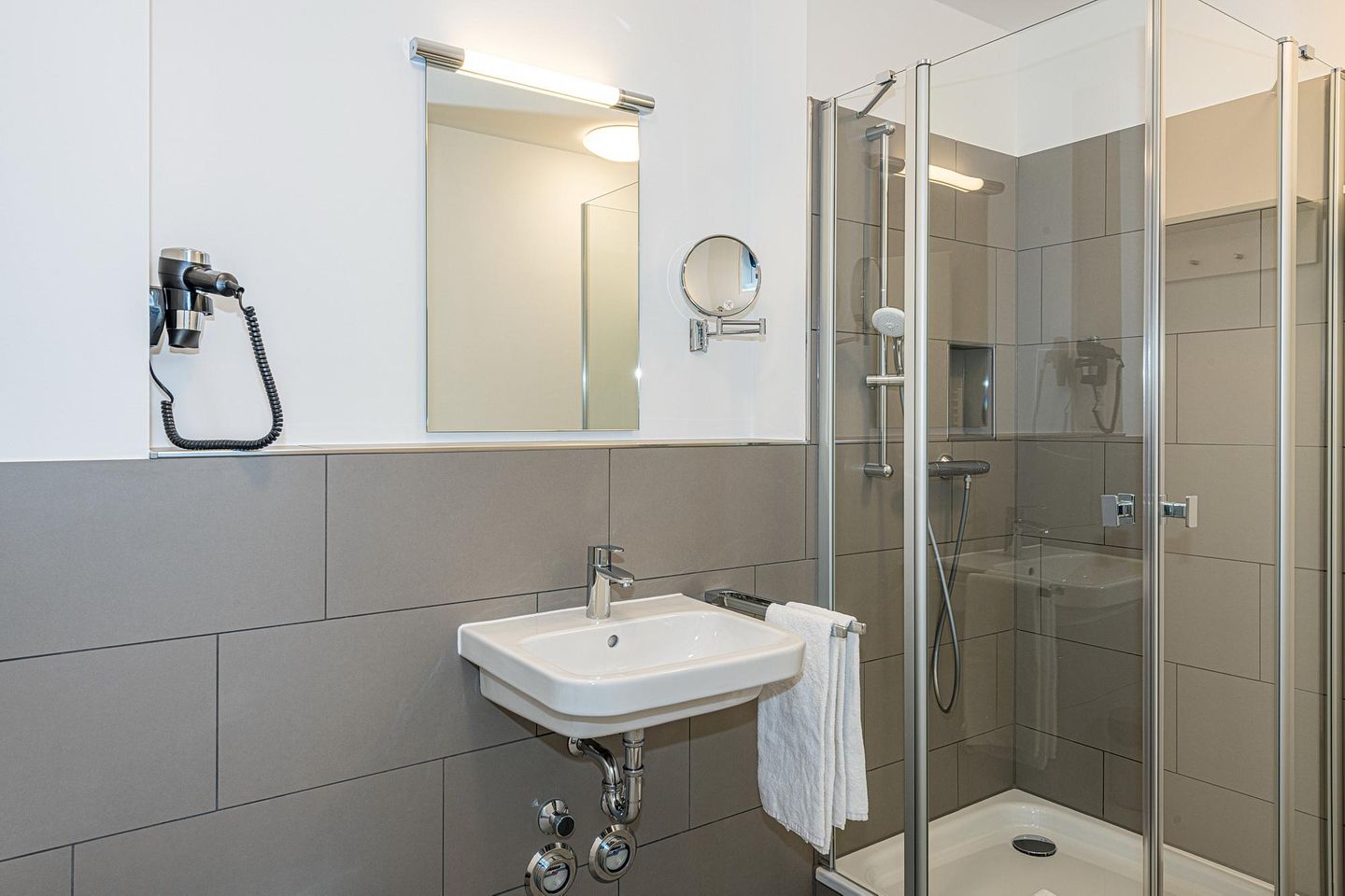Deichhäuser Anna Küste Deichhäuser Anna Küste 7-21 Bensersiel - Badezimmer mit Dusche, Waschbecken, Föhn und Spiegel
