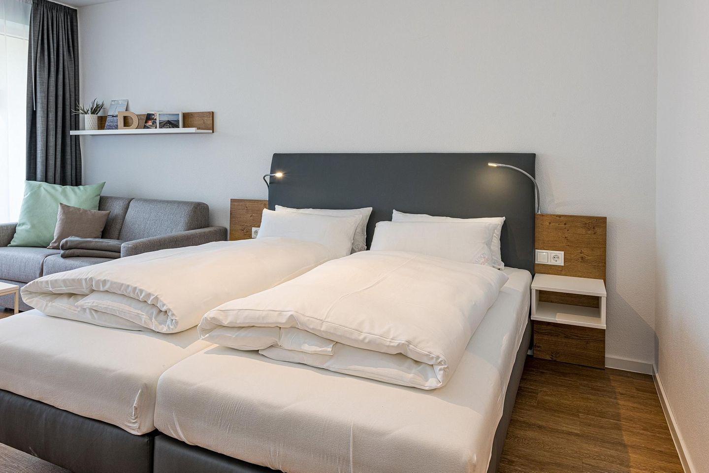 Deichhäuser Anna Küste Deichhäuser Anna Küste 8-22 Bensersiel - Wohn-Ess-Schlafbereich mit Sofa, Esstisch, Sitzgelegenheit und Doppelbett sowie Zugang zum Balkon