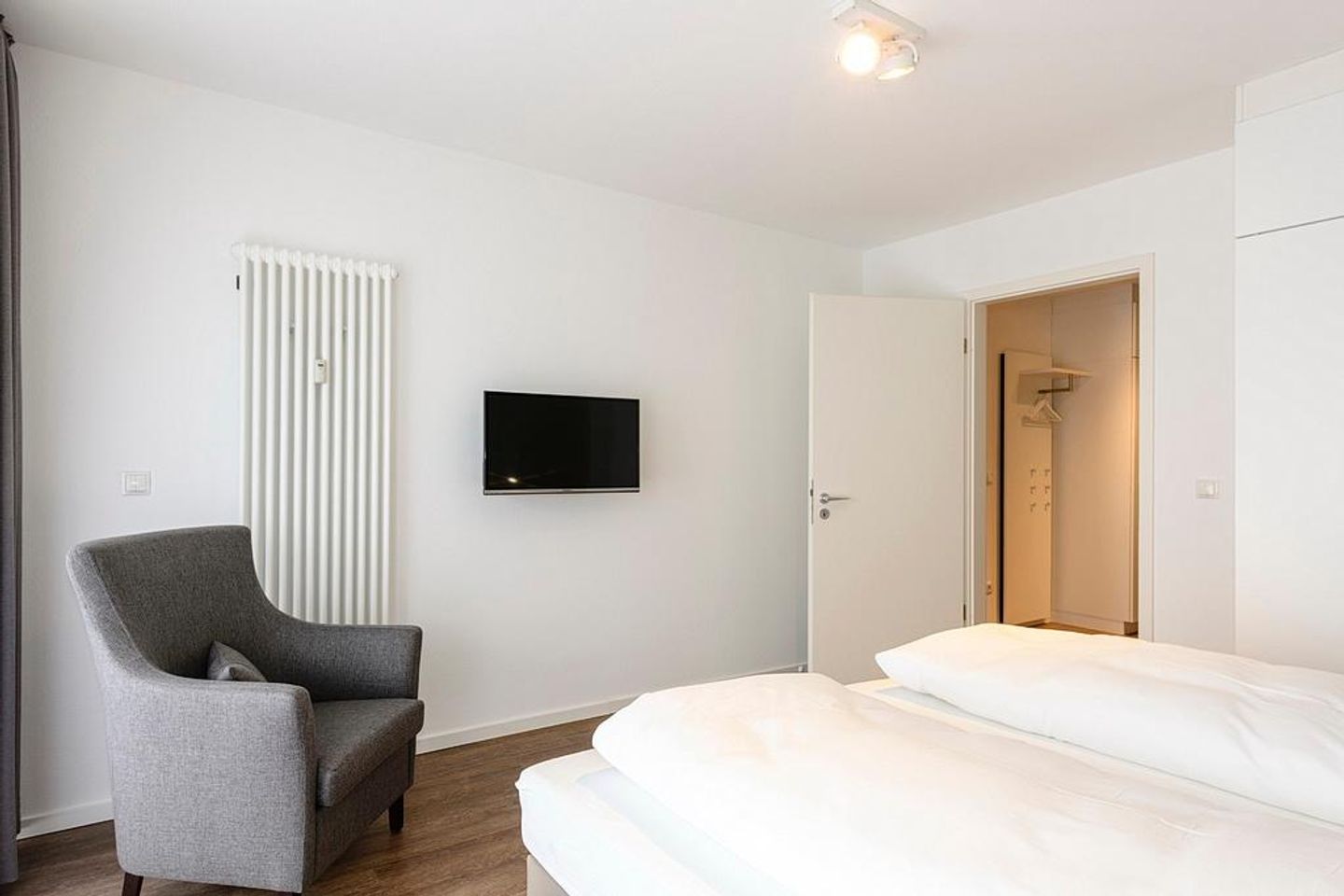 Deichhäuser Anna Küste Deichhäuser Anna Küste 1-21 Bensersiel - Schlafzimmer mit Sessel, Doppelbett und TV