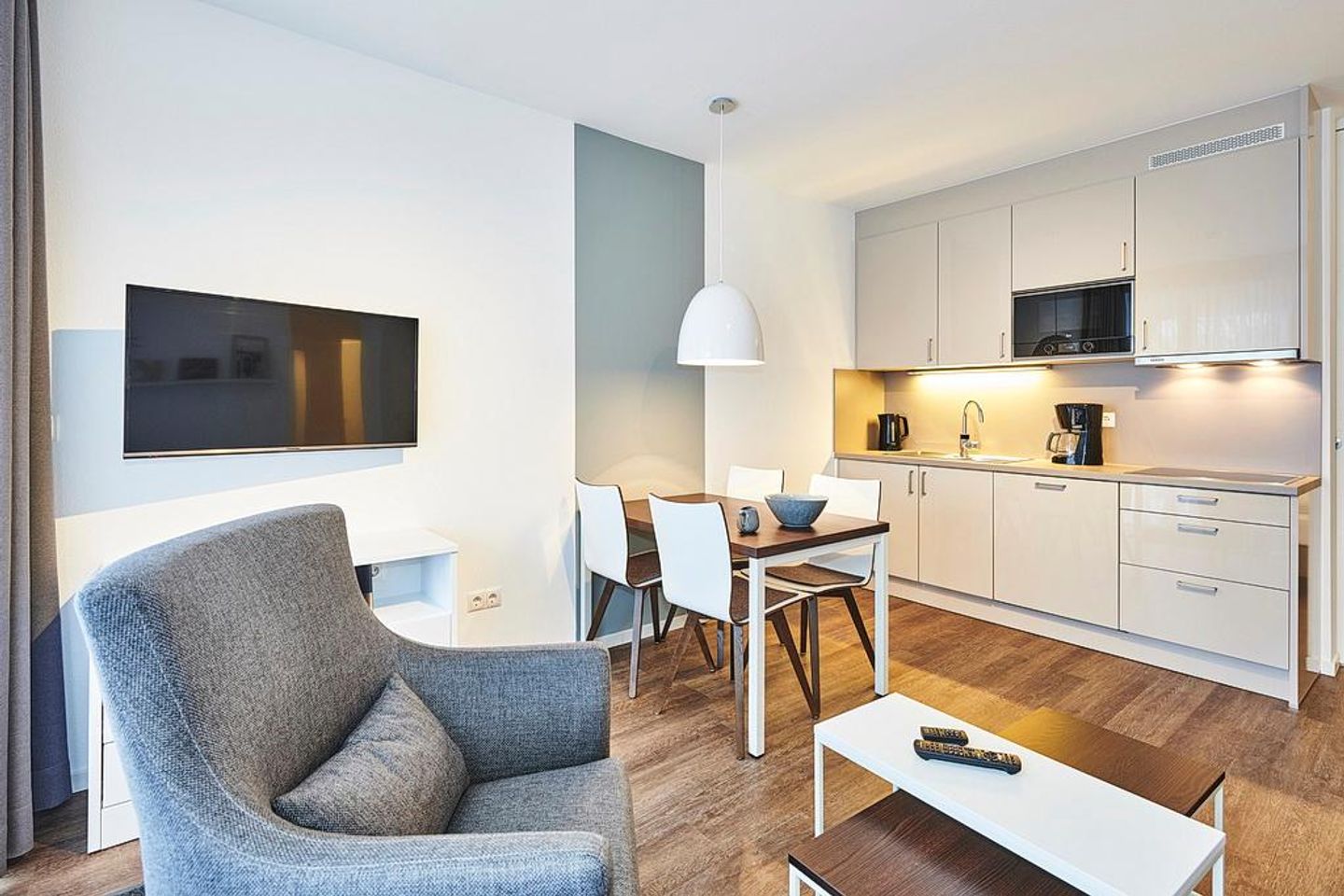 Deichhäuser Anna Küste Deichhäuser Anna Küste 2-11 Bensersiel - Wohn/Essbereich mit Sessel, Esstisch, Küchenzeile und TV