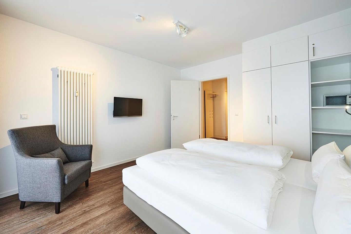 Deichhäuser Anna Küste Deichhäuser Anna Küste 2-11 Bensersiel - Schlafzimmer mit Doppelbett, Sessel und Kleiderschrank