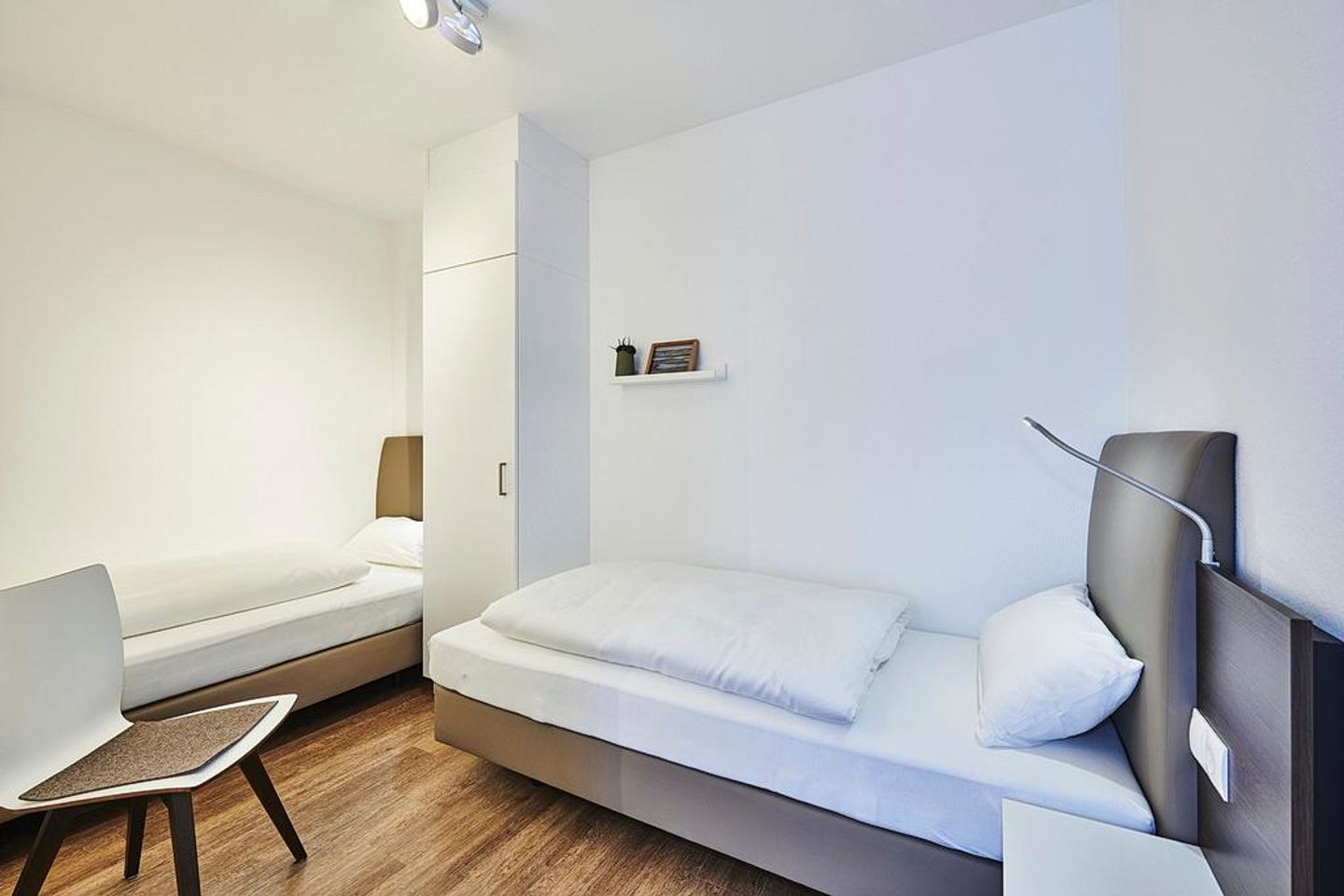 Deichhäuser Anna Küste Deichhäuser Anna Küste 2-11 Bensersiel - Schlafzimmer mit zwei Einzelbetten, Kleiderschrank und Stuhl