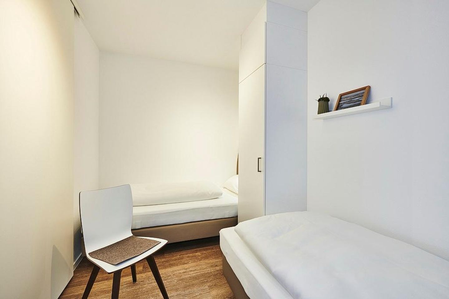 Deichhäuser Anna Küste Deichhäuser Anna Küste 2-11 Bensersiel - Schlafzimmer mit zwei Einzelbetten, Stuhl und Kleiderschrank